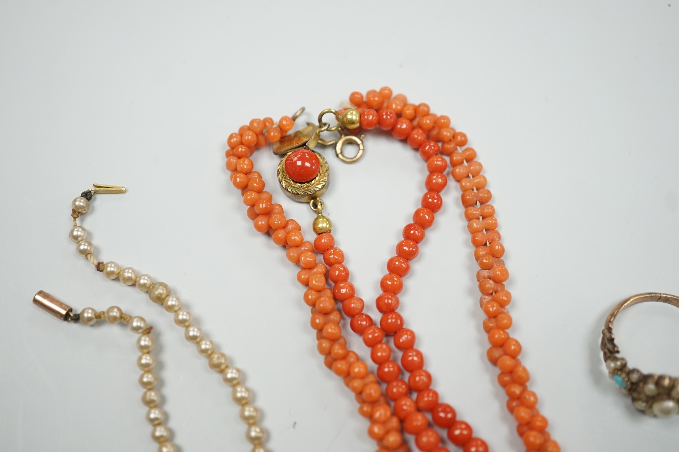 A yellow metal, seed pearl and red stone set 'bird on a branch' brooch, width 30mm, two coral bead necklaces, an enamelled white metal imp and shell brooch, three rings, a marcasite brooch and a simulated pearl necklace.